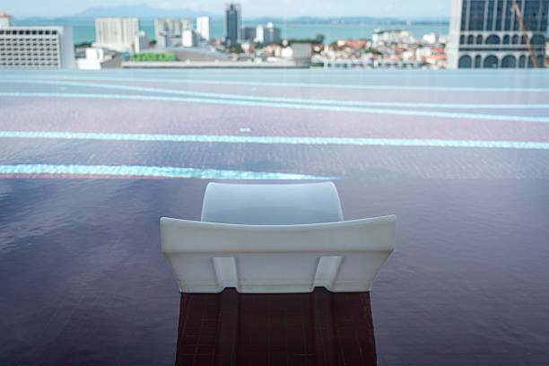 Plastic lounge chair inside infinity swimming pool with city view. Holiday or vacation concept.