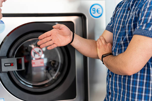 istock Laundromat worker showing washing machine to customer 2236033369