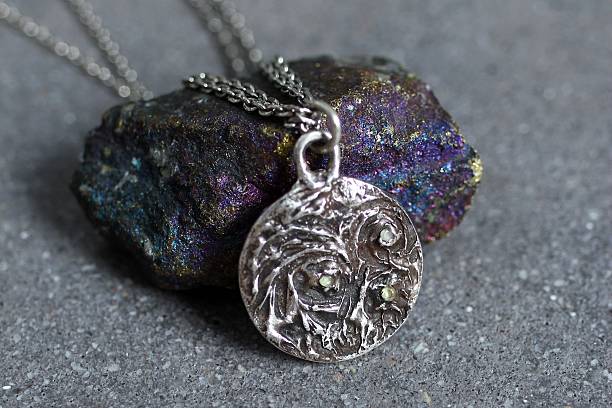Silver Pendant with a Patterned Design on a Chain, Lying on a Stone, Artistic Jewelry.