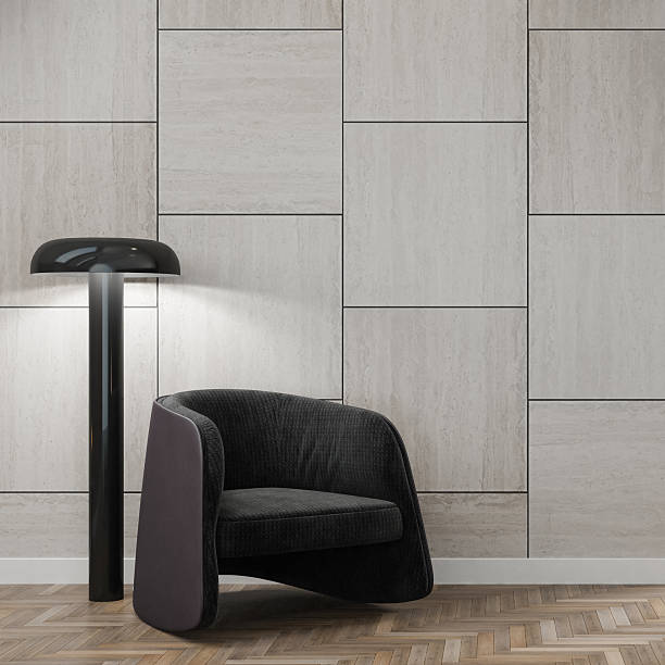 Stylish modern minimal interior featuring a sculptural armchair, black floor lamp, and a textured wall clad in large stone tiles arranged in a staggered pattern. The warm lighting and herringbone wood flooring enhance the refined aesthetic, while the clean composition and neutral tones provide ample copy space for branding, editorial overlays, or app interface backgrounds.