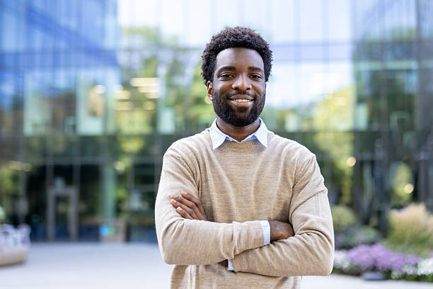 istock A confident man smiles, arms crossed, outside a modern building. 2236036085