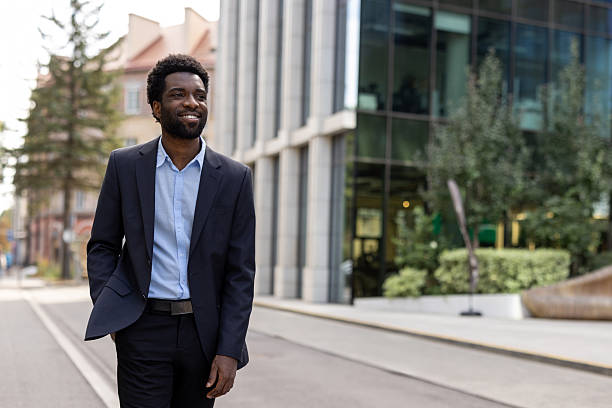 istock Confident businessman walking outdoors near a modern office building with greenery 2236036177