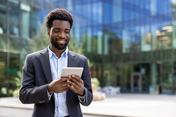 istock Smiling businessman using a tablet outdoors near a modern office building 2236036179