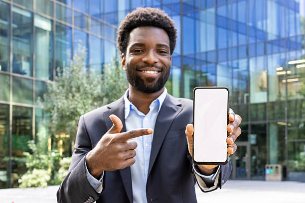 istock Happy businessman in a suit showing a smartphone with blank screen. 2236036184