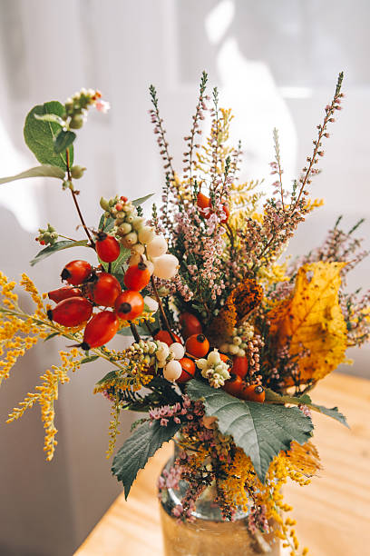 Autumn bouquet on a table illuminated by sunlight near a window, creating a warm, cozy, and atmospheric seasonal still life scene.