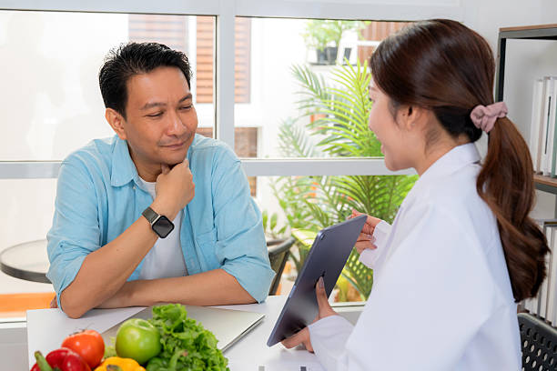 istock Asian nutritionist using tablet to explaining personalized meal plan with AI to patient during healthcare consultation, healthy lifestyle, woman dietitian showing nutrition plan with AI on tablet. 2236038013