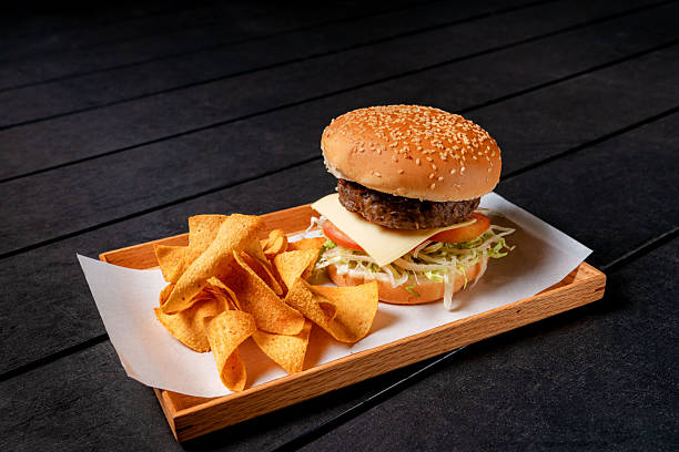 istock Hamburger with Corn Chips on a Wooden Serving Tray 2236038078