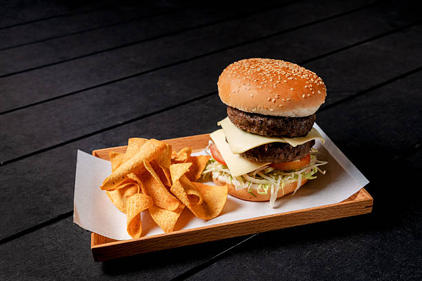 istock Hamburger with Double Beef Patty and Corn Chips on a Wooden Serving Tray 2236038083