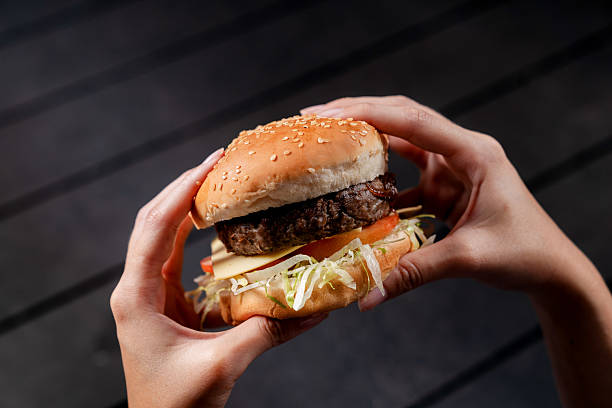 istock Hands Holding a Large Hamburger with a Sesame Seed Bun 2236038087