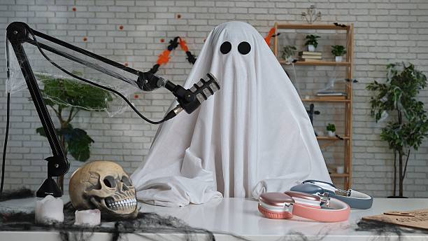 istock Funny ghost in a white sheet recording a podcast or blog 2236038396
