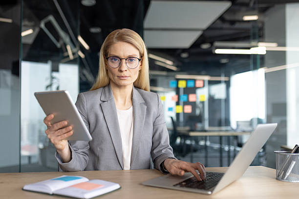istock A professional woman in a suit using a laptop and tablet in her office, working 2236038698