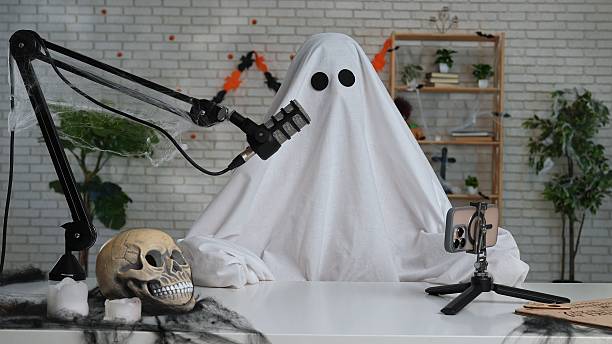 istock Funny ghost in a white sheet recording a podcast or blog 2236038991