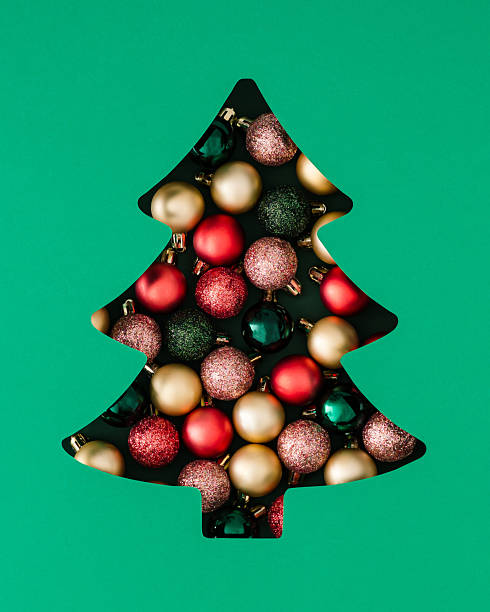 istock Winter composition with Xmas baubles visible through a Christmas tree shaped gap on green background. Minimal Christmas and New Year concept. Creative festive holiday layout. Flat lay, top view. 2236041731