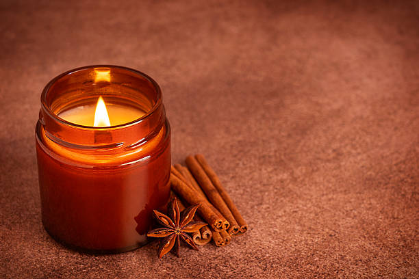 istock Aromatic candle with cinnamon sticks and star anise on brown table with copy space 2236044101