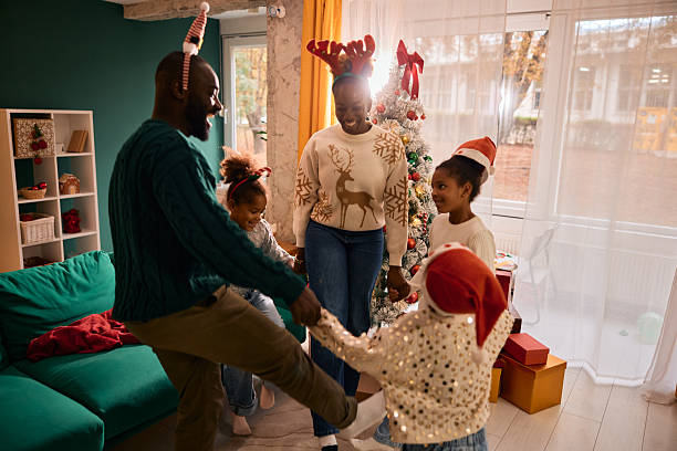 istock Black family dancing around Christmas tree during holidays 2236044922