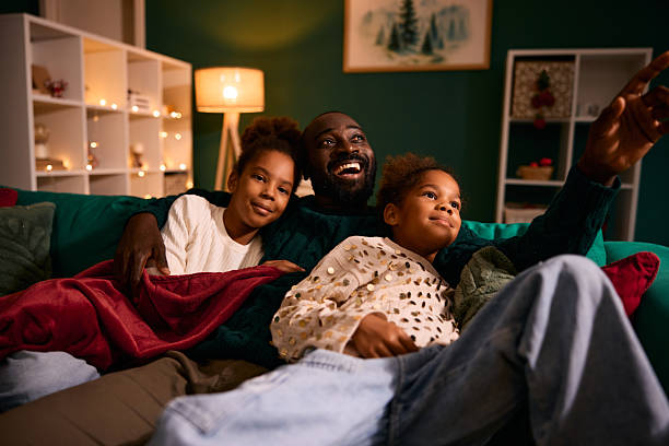 istock Happy father and daughters watching TV at home 2236045016