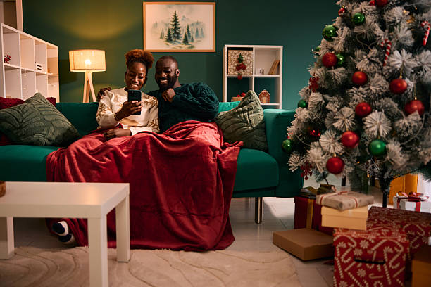 istock Black couple relaxing at home watching smartphone during Christmas 2236045172