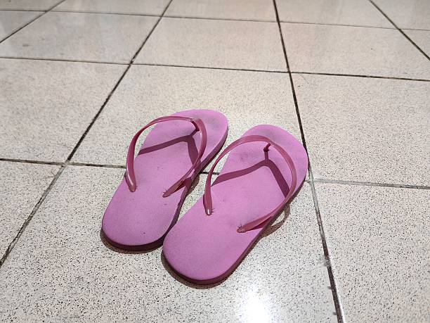 A pair of pink slippers on a ceramic floor.