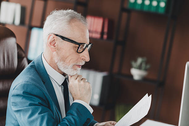 istock Successful businessman reviewing documents attentively in a formal office setting showcasing professionalism and focus 2236048686