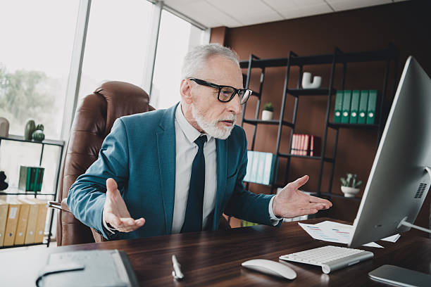istock Mature businessman in formalwear gesturing while working in his modern office with desktop computer on desk 2236048703