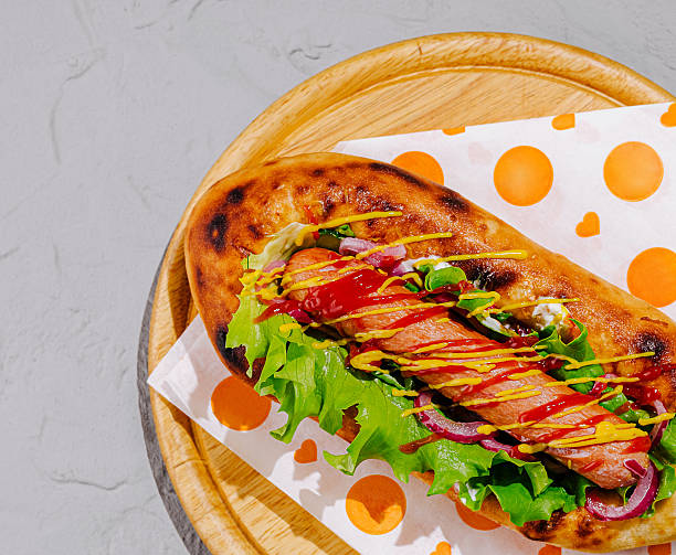 Delicious hot dog loaded with toppings on a wooden board