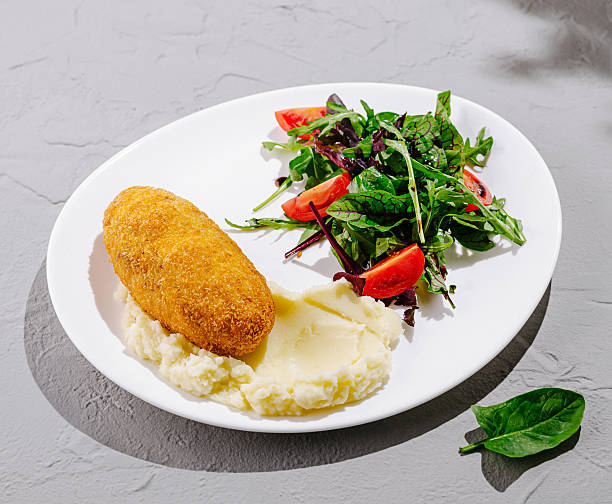 Crispy croquette served with mashed potatoes and fresh salad on a plate