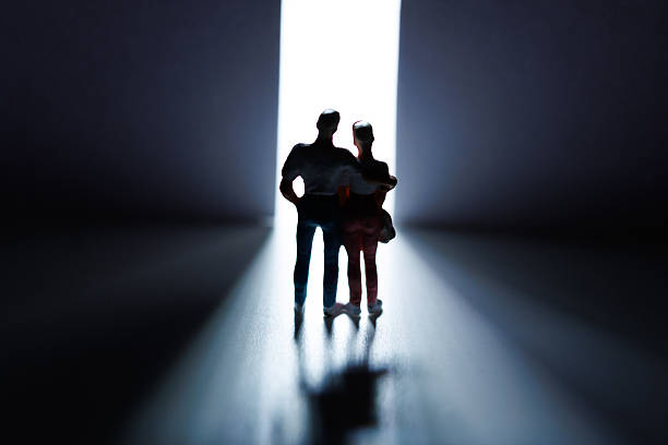 istock Young couple stands together in a dimly lit space illuminated by a bright light from an open door 2236051075