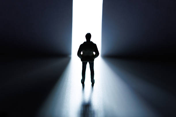 istock Man standing in front of open door with lights coming through 2236051078