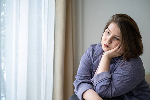 istock Sad plus size woman looking out window thinking about life changes, mental health, depression, loneliness, emotional burnout, body positivity, solitude, female introspection at home 2236053136