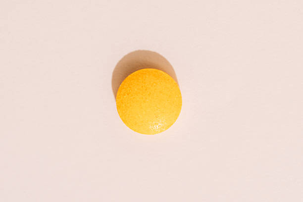 istock Single orange tablet on beige background, top view with hard shadow 2236053405