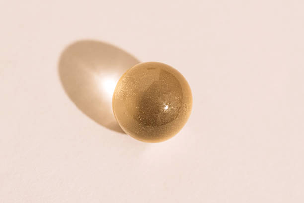 istock Golden softgel sphere on beige background with glossy highlight 2236053494