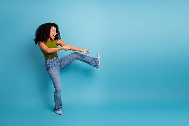 istock Charming young woman in casual fashion posing dynamically against a solid blue background with vibrant energy 2236059558