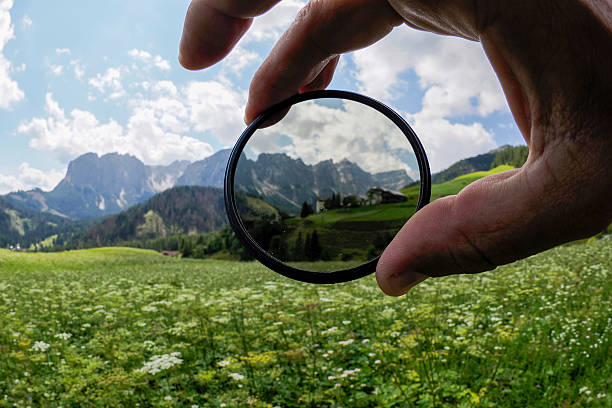 istock Hand holding polarizer filter showing the difference of sky contrast in mountain background 2236061327