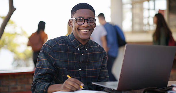 istock Students, man and happy with laptop on campus for exam study, test preparation and productivity. Portrait, books person learning with computer at university for knowledge, essay research or education 2236063190