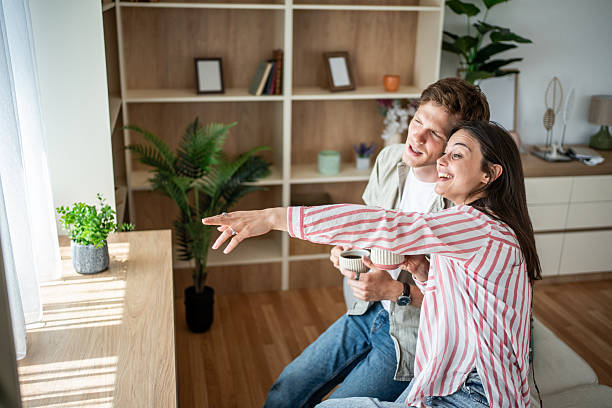 istock Cheerful young couple pointing and smiling while drinking coffee in their apartment 2236064147