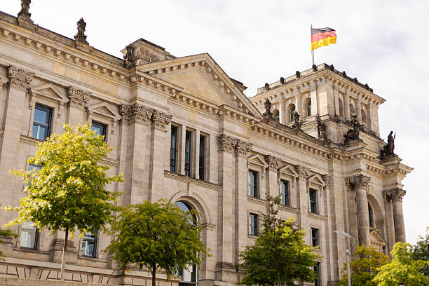 Berlin, Germany - September 1, 2025: The Reichstag building in Berlin, showcasing its impressive architecture under a clear blue sky. The German flag flies proudly above the historic structure.