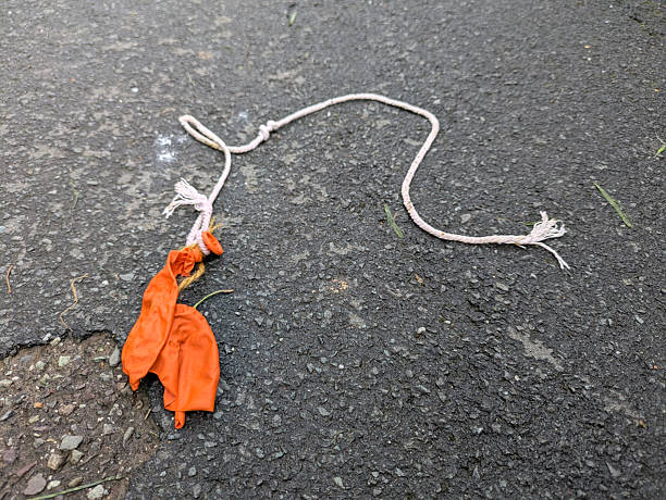 A popped children's balloon on white string abandoned on a path