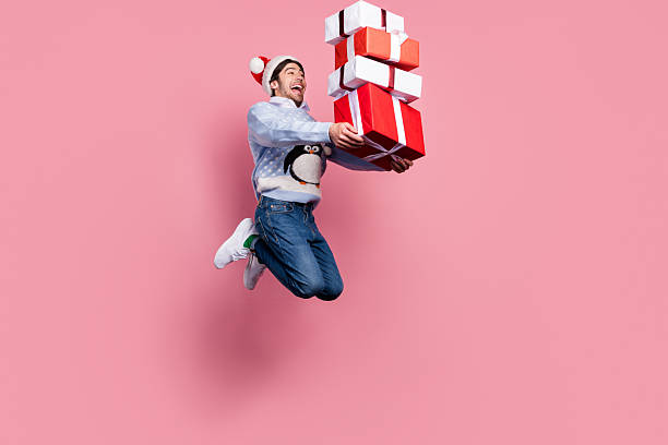 istock Photo of impressed cute man dressed blue christmas pullover jumping holding presents pile smiling isolated pink color background 2236073502