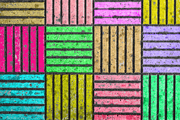 Colorful blocks create a cheerful pattern on the pavement, featuring pink, green, yellow, purple, and brown sections with distinct lines. This lively design adds character to the urban landscape.