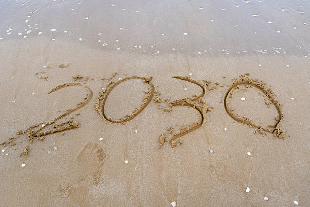 istock 2030 numbers written on sand. Sea beach 2236076566