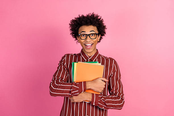 istock Smiling young man holding colorful notebooks against pink backdrop expressing enthusiasm and positivity with cheerful energy 2236077144