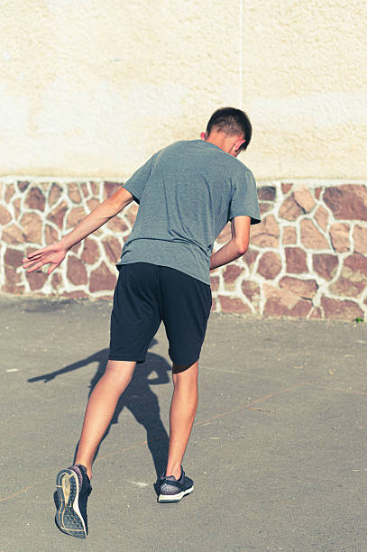 istock Teenager playing outdoors, bending down,  shadow cast on the ground. Sunny day activity. 2236078509