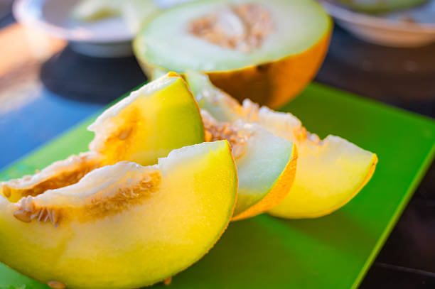 Sliced wedges of ripe, juicy melon arranged on a green cutting board, ready to serve, showcasing fresh fruit and healthy eating.