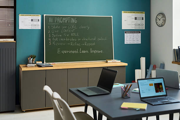 istock Empty Classroom with Laptops and Blackboard Displaying AI Prompting Instructions 2236081652