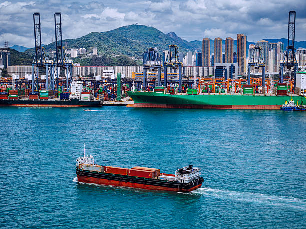The image displays a bustling Hong Kong industrial port with large container ships, cranes, and scenic mountainous backgrounds, demonstrating a dynamic setting of shipping and global industry.