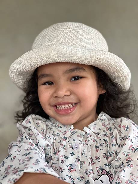 Portrait of a little girl with white hat smiling at the camera