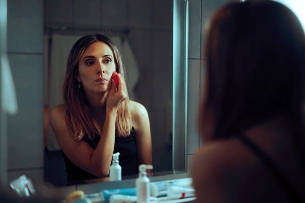 istock Woman Using Sponge to Apply Foundation in the Mirror 2236082913