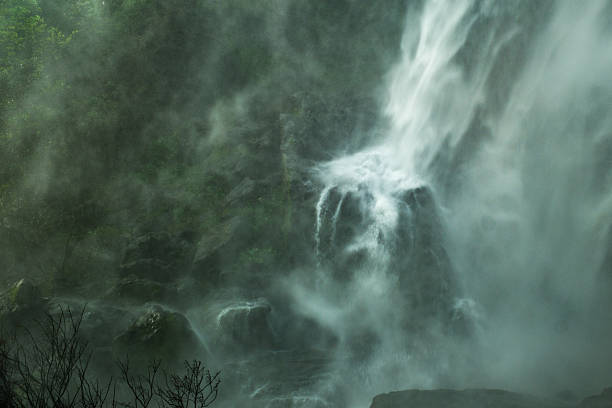 A waterfall with mist and fog in the background. The waterfall is surrounded by rocks