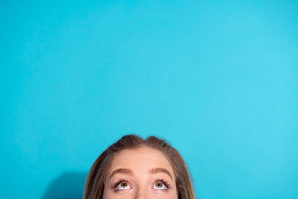 istock Young woman looking up with curious expression against bright blue background, conveying contemplation and youth 2236083166