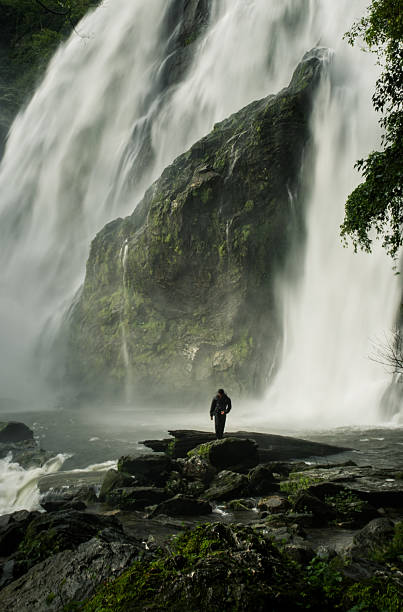 istock A man stands in front of a waterfall   waterfall , 2236084388